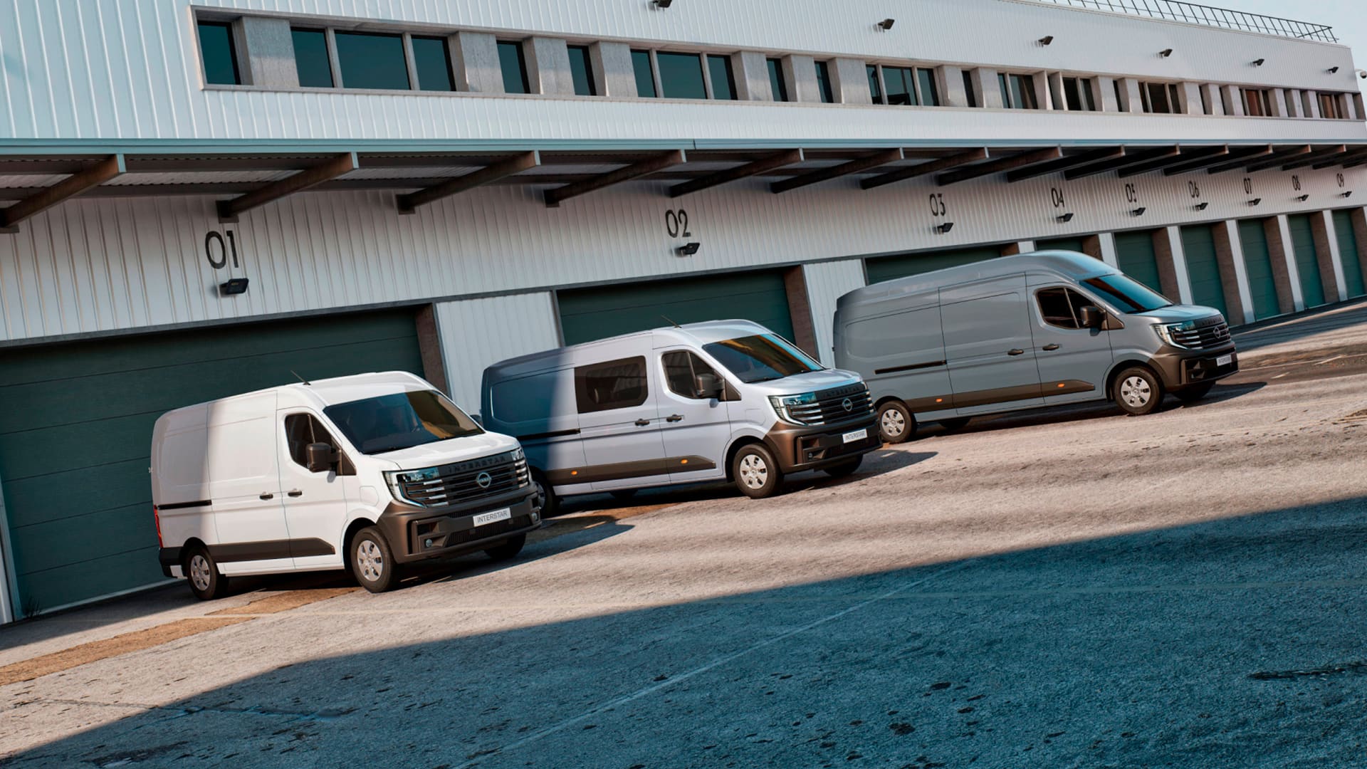 Des fourgons Nissan Interstar (L1H1 + L2H2) et des fourgons à double cabine sont garés devant un entrepôt.